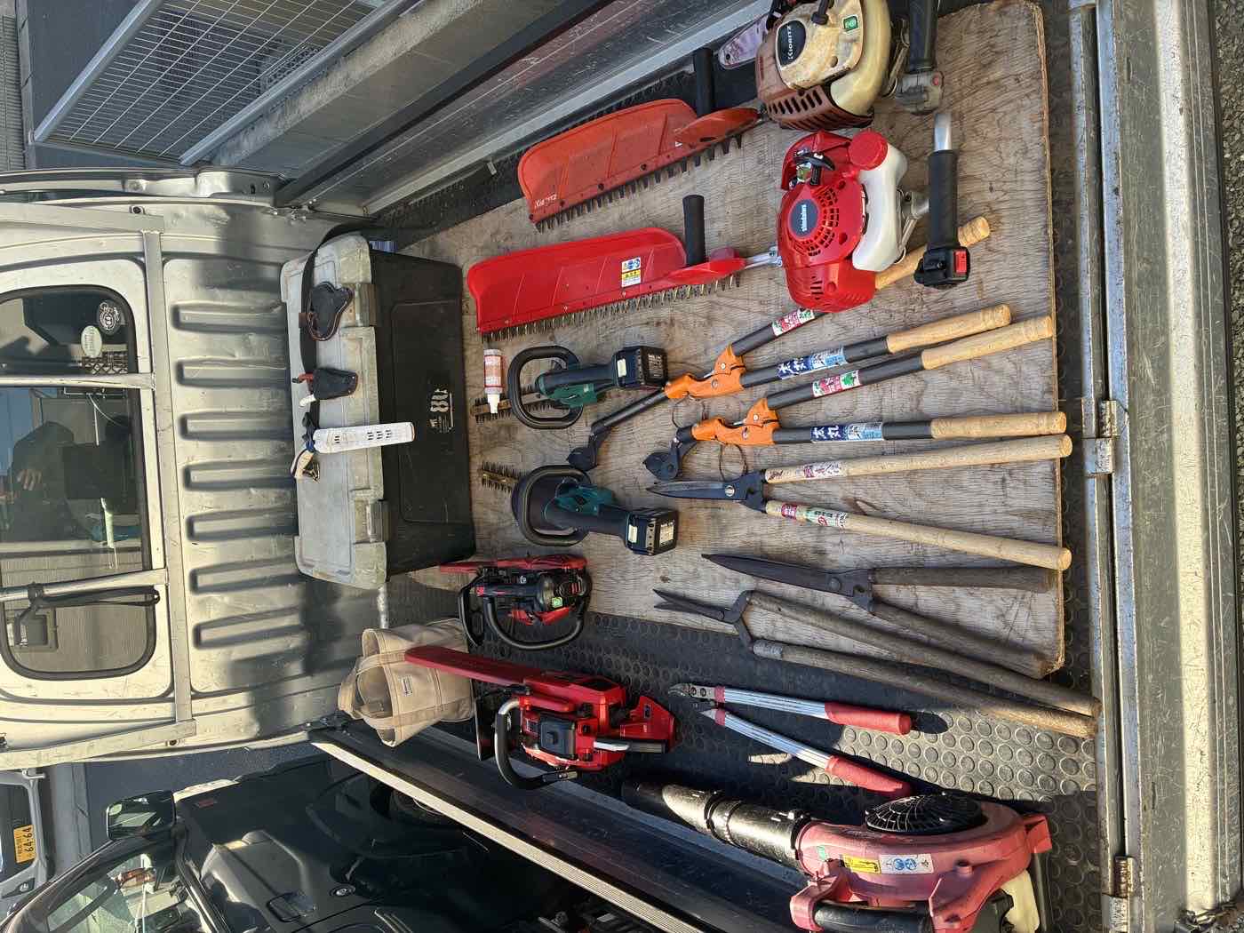 トラックの荷台に整然と並べられた剪定・伐採の道具一式